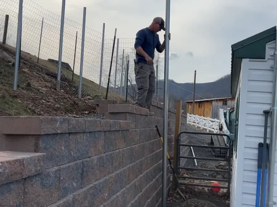 Setting fence posts above a block retaining wall on a farm property