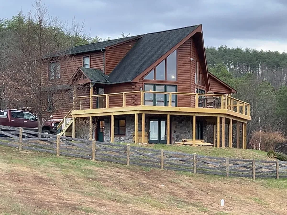 Split-rail fence line running to a log home in the mountains