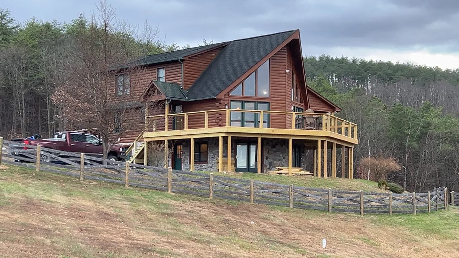Split-rail fence line running to a log home in the mountains