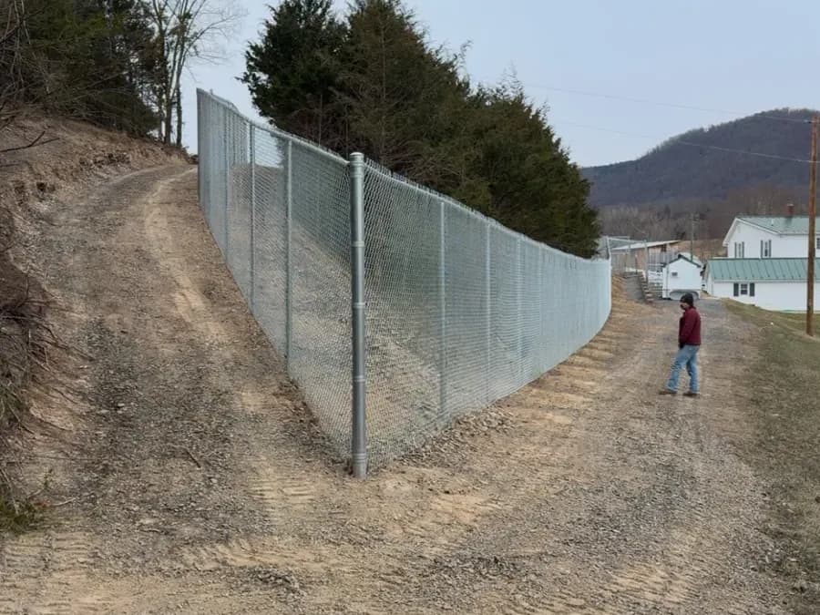 Galvanized chain-link fence stepped down a graded slope