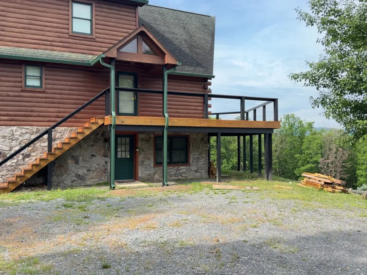Stained deck and stairs wrapping a timber lodge on a stone foundation