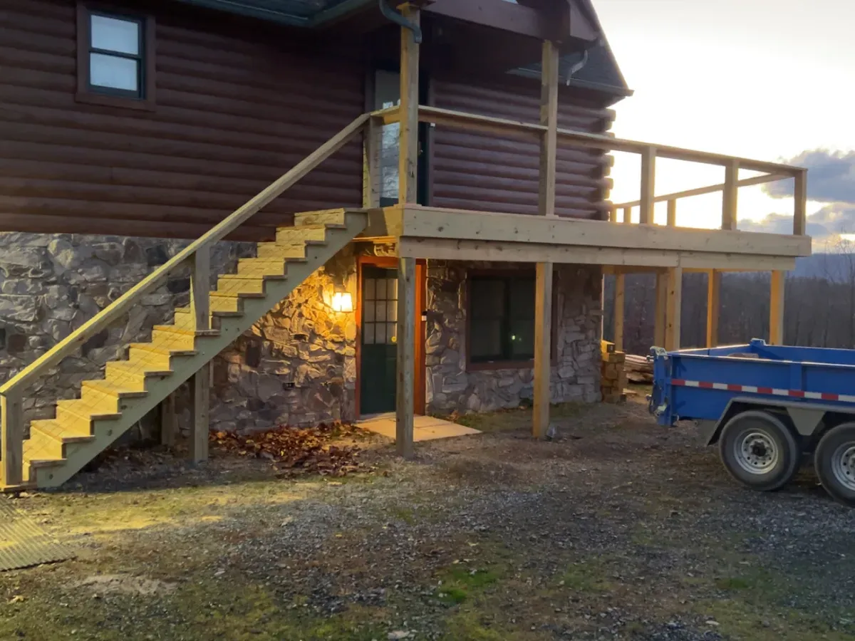 New porch stairs and framing going up on a stone-chimney lodge