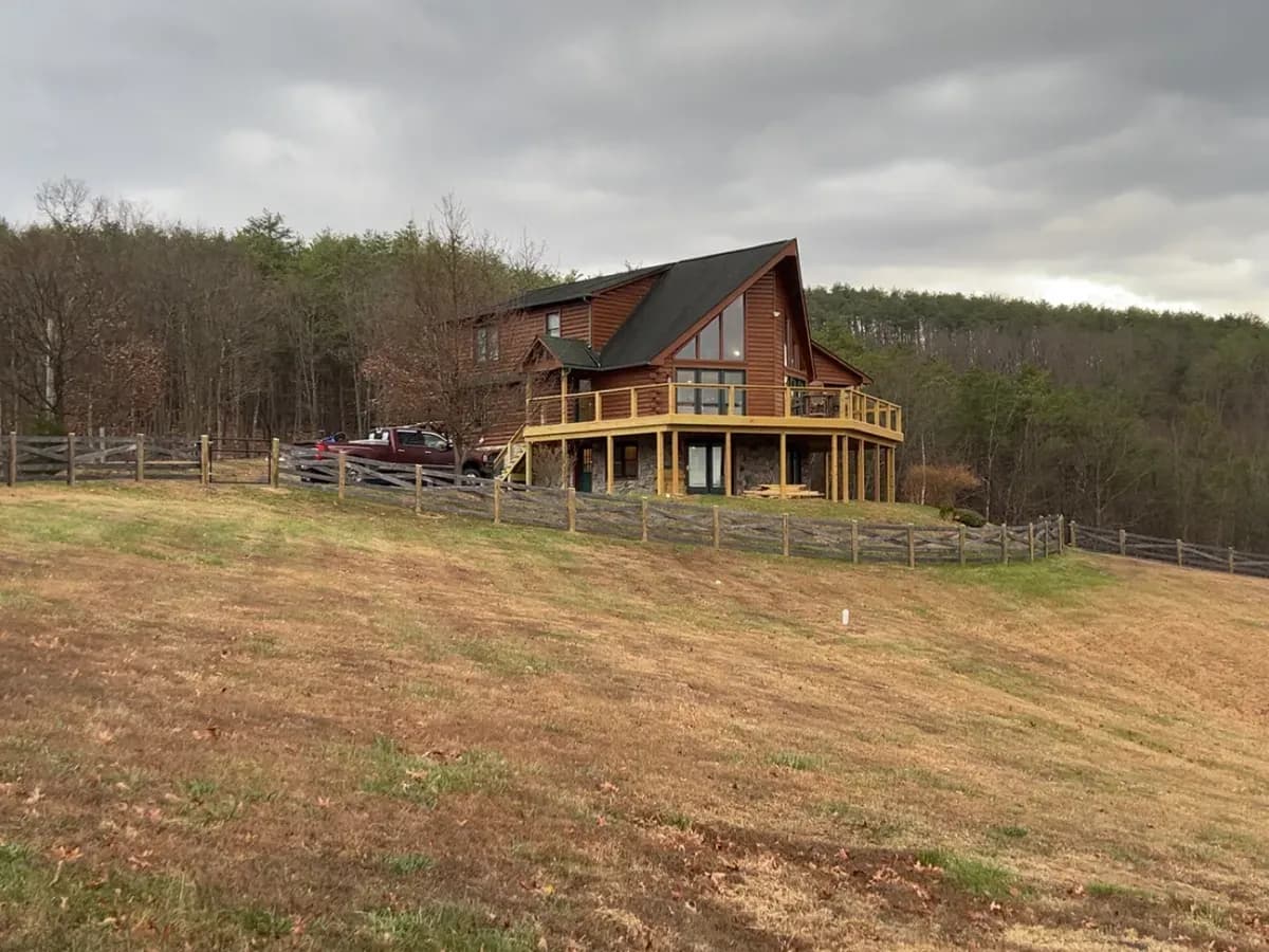 New wraparound deck on a log home with a split-rail fence line