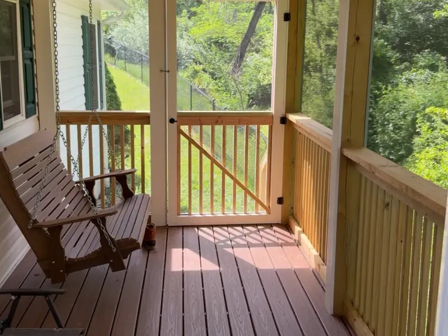 Screened porch with a hanging porch swing and composite decking