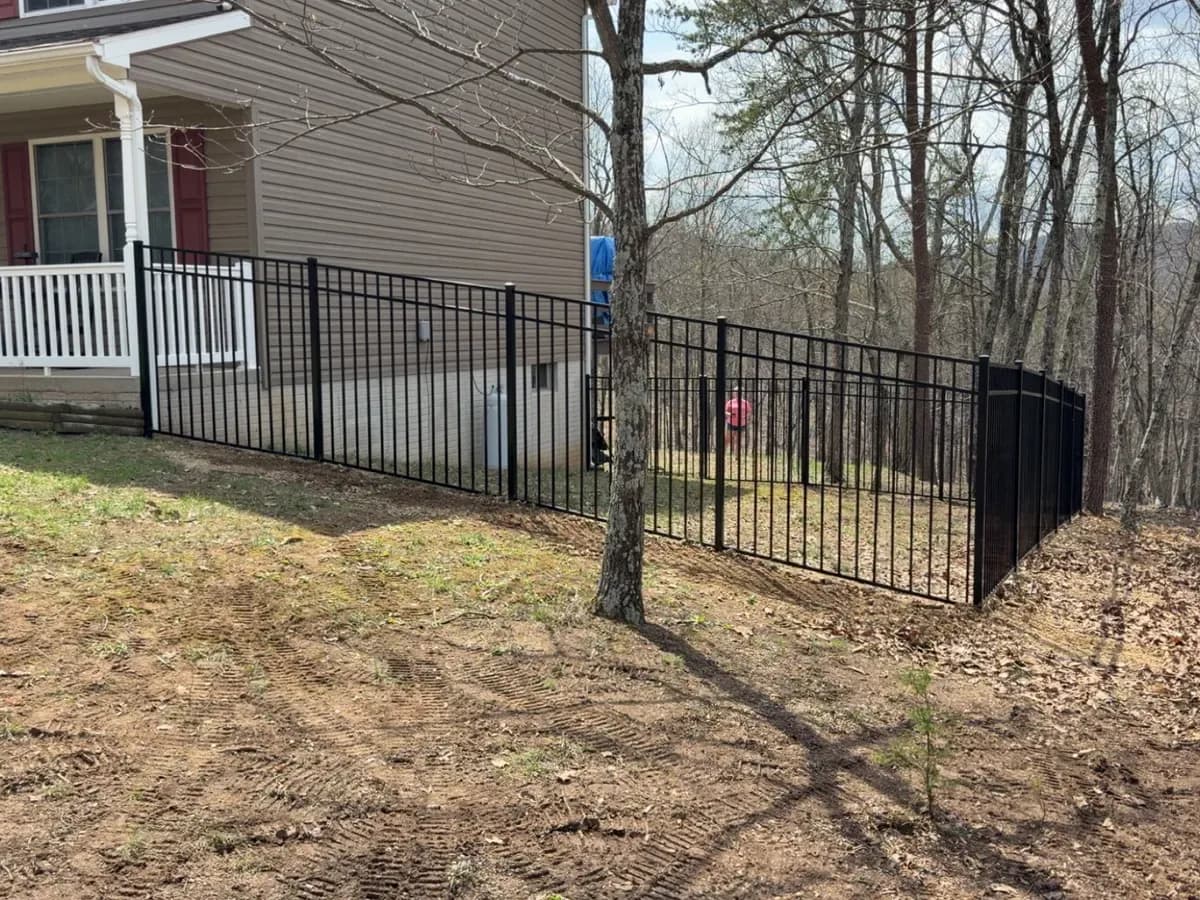 Black ornamental metal fencing with a covered porch behind