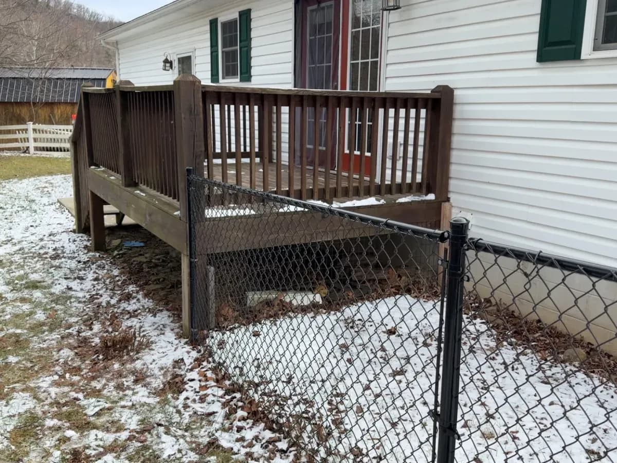 Black chain-link fence beside a dark-stained deck in winter