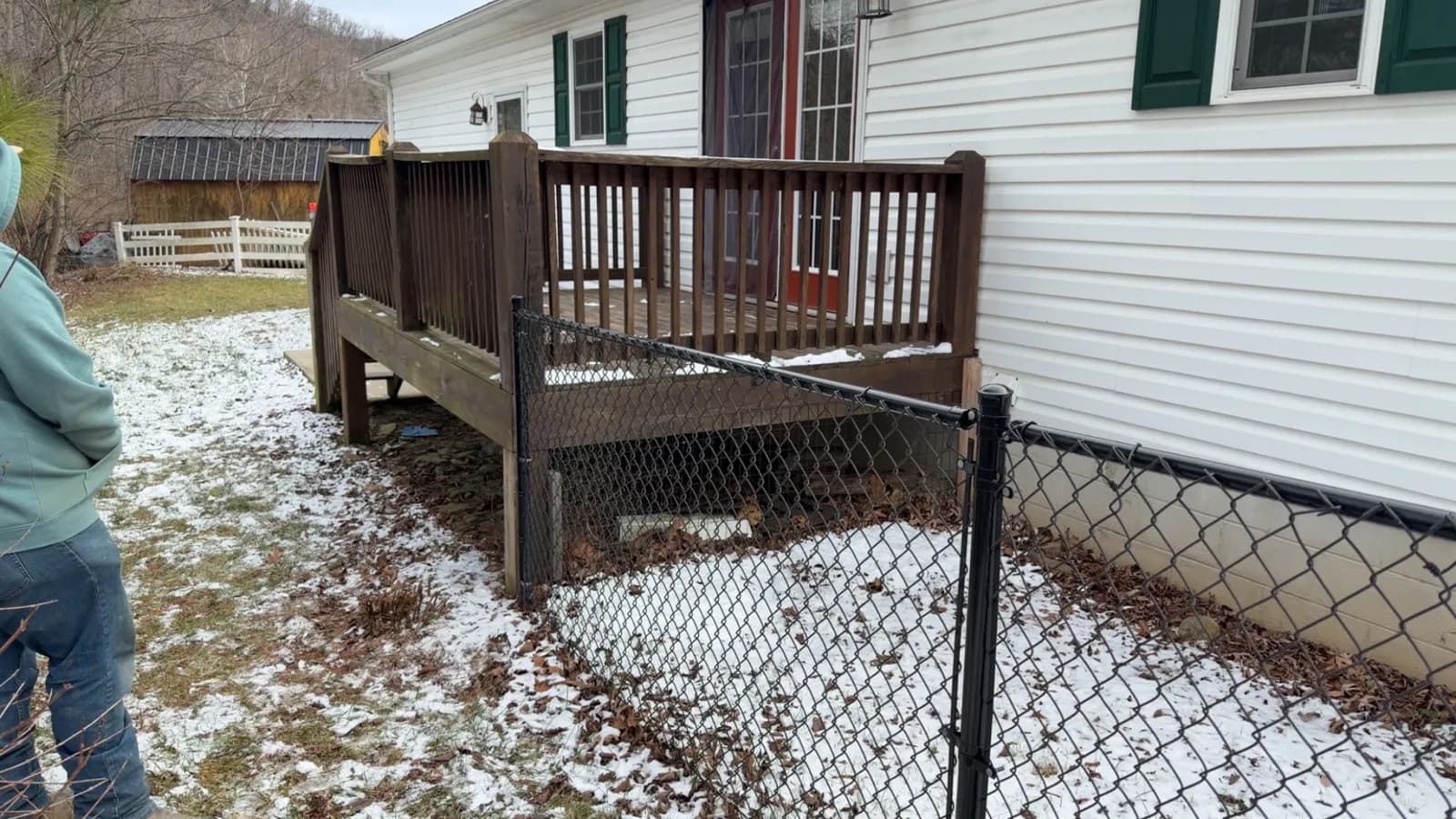 Black chain-link fence beside a dark-stained deck in winter