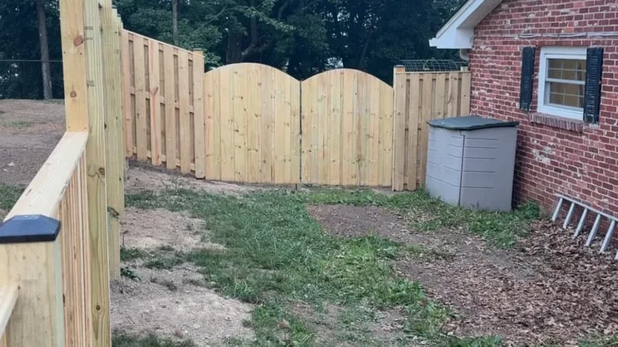 New wood shadowbox privacy fence with custom arched double gate at a brick home