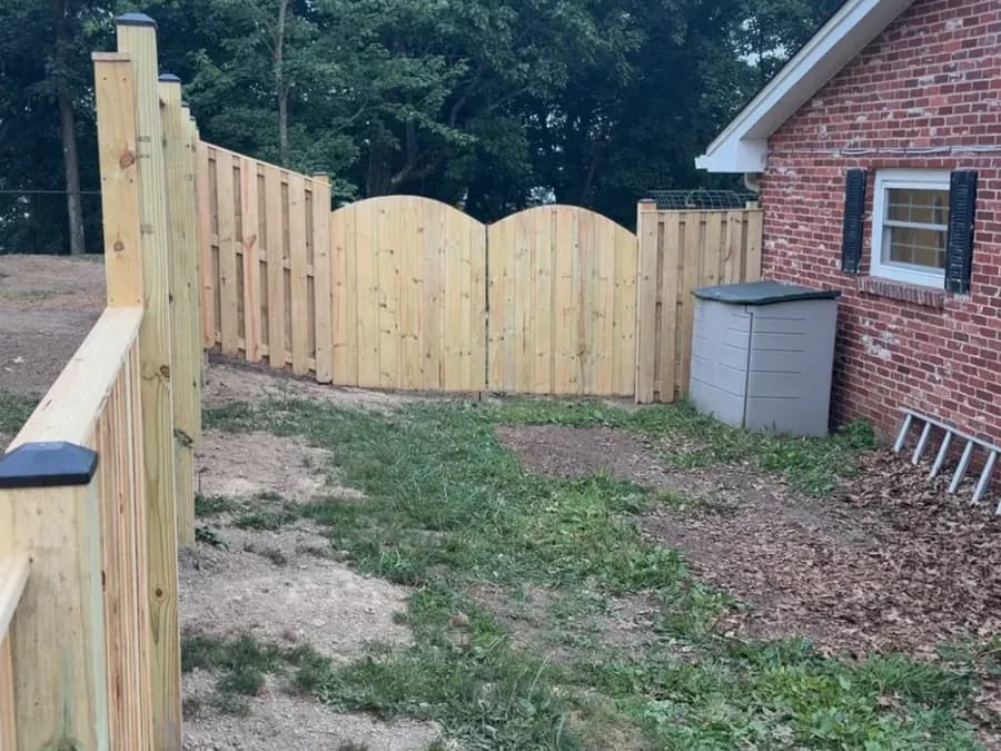 New wood shadowbox privacy fence with custom arched double gate at a brick home